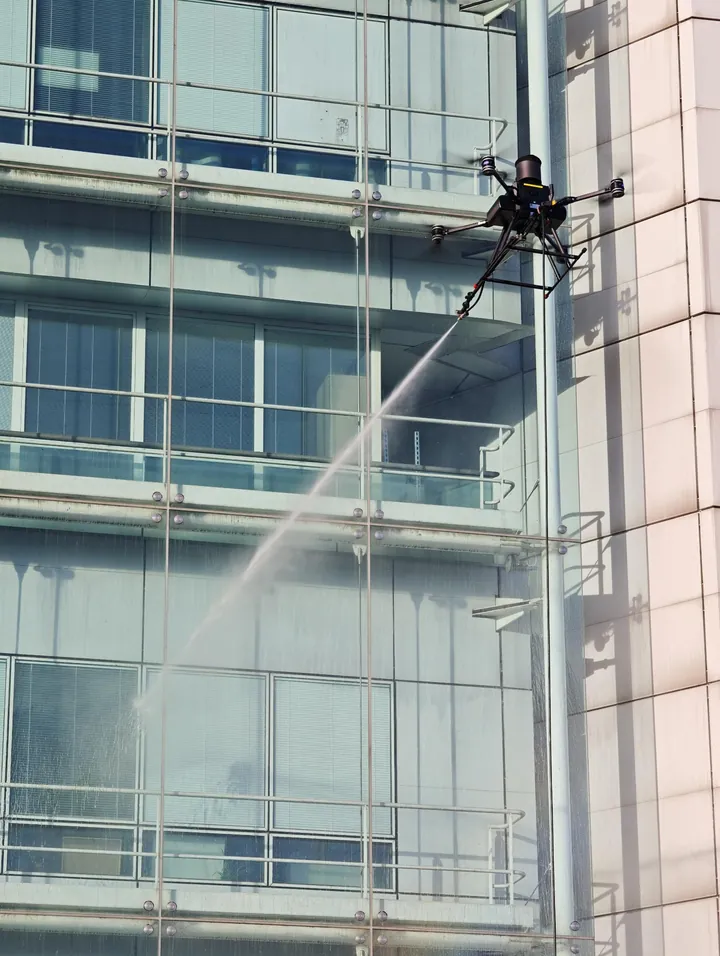 Tethered drone spraying the glass curtain wall from a few metres away