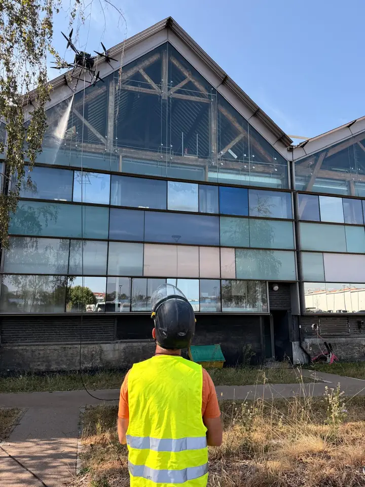 Operator watching a drone clean a large glass gable