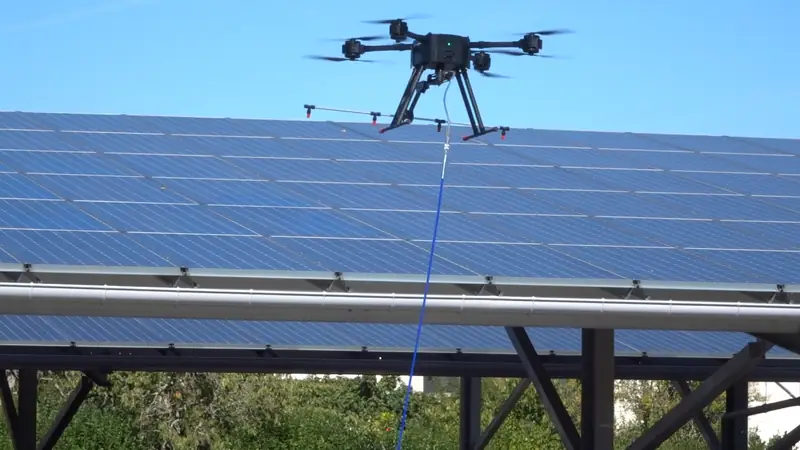 Tethered drone cleaning solar panels on a carport canopy