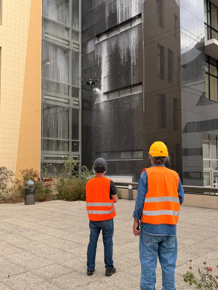 Two operators supervising drone cleaning in a courtyard