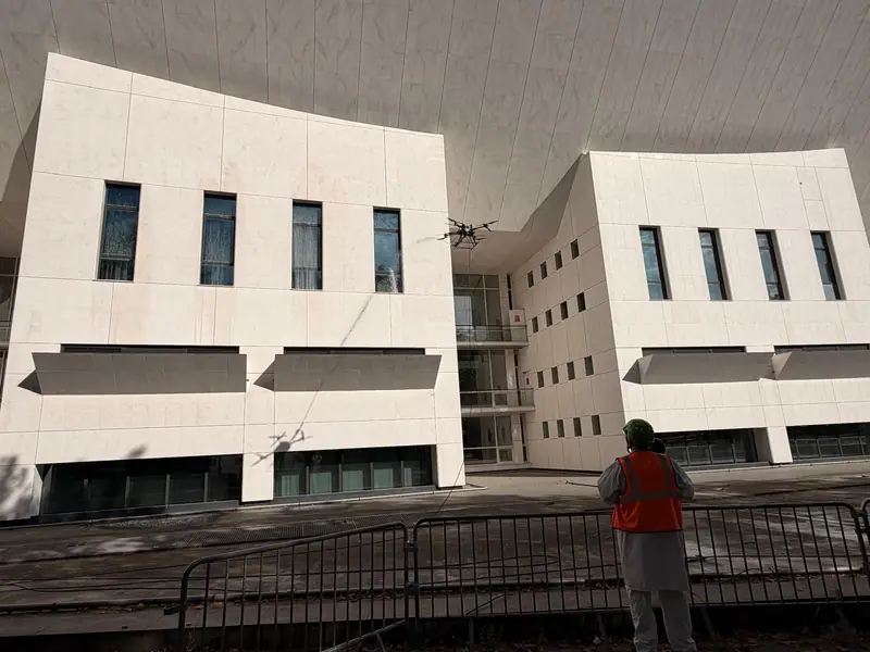 Ground crew in front of a white building with the drone above